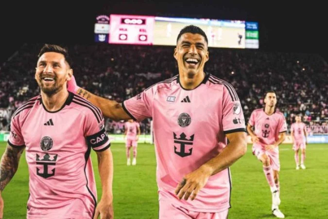 Lionel Messi e Luis Suárez estão dentro do campo, lado a lado, vestem uniforme cor de rosa do Inter Miami e sorriem após partida; dupla anunciou fundação de novo clube de futebol no Uruguai